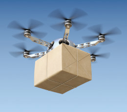 Drohne fliegt mit Paket vor einem blauen Himmel.