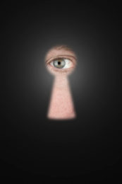 Mann blickt mit seinem Auge durch ein Schlüsselloch.