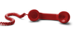 Liegender roter Telefonhörer an der Telefonschnur.