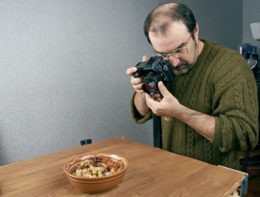 Mann fotografiert Essen, das auf einem Tisch steht.