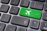 Grüne Taste mit Flugzeug-Symbol auf einer schwarzen Tastatur.