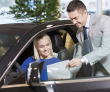 Autoverkäufer übergibt Frau, die im Auto sitzt ein Angebot