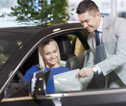 Autoverkäufer übergibt Frau, die im Auto sitzt ein Angebot