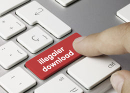 Finger drück auf eine rote Taste auf einer Tastatur mit der Aufschrift "illegaler download".