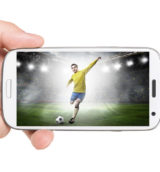 Hand hält weißes Smartphone auf dem ein Fußballspieler zu sehen ist