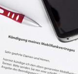 Kulli und Smartphone liegen auf einer schriftlich verfassten Kündigung eines Mobilfunkvertrages