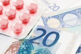 Rote Tabletten liegen auf 20 Euro Scheinen