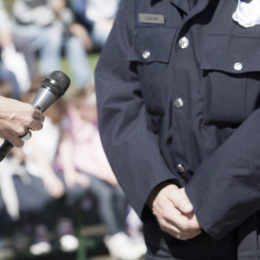 Eine Person hebt einer anderen Person in Uniform ein Mikrofon hin