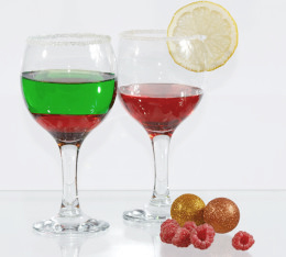 Zwei Gläser mit jeweils einem roten und einem grünen Getränk. Daneben liegen einige Himbeeren.