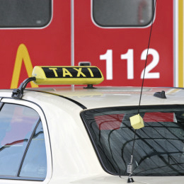 Ein Taxi das vor einer roten Tür mit der Norufnummer 112 darauf steht