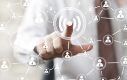 Mann in Hemd und Krawatte drückt mit dem Finger auf ein W-Lan-Symbold, das mit vielen Menschen-Symbolen verbunden ist