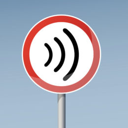 WLAN-Zeichen auf einem weißen runden Schild mit rotem Rand. Es befindet sich vor einem blauen Hintergrund