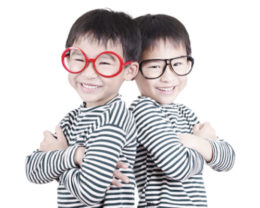 Zwillingspärchen, wobei Einer eine rote und der Andere eine schwarze Brille trägt. Verwechslungsgefahr