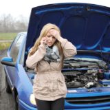 junge Frau hat Autopanne und telefoniert mit dem Handy