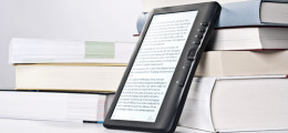 E-Book-Reader steht vor mehreren Büchern
