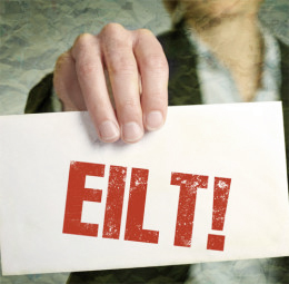 Eine Person hält ein Schild in der Hand mit der Aufschrift "EILT!"