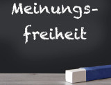 schwarze Tafel mit weißer Aufschrift "Meinungsfreiheit", darunter weiße Kreide