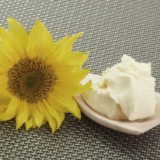 Holzlöffel mit Margarine liegt neben einer Sonnenblume
