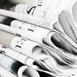 Mehrere gefaltete Zeitungen liegen auf einem Stapel