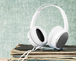 weiße Kopfhörer auf einem Stapel Schallplatten vor einer mintfarbenen Wand