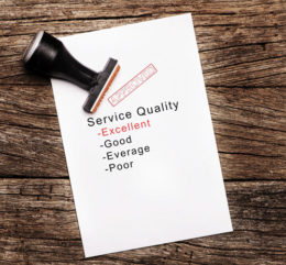 Stempel mit "Approved" liegt auf Zettel mit dem Schriftzug "Service Quality".