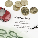 Kaufvertrag, auf dem ein rotes Auto steht sowie 100-Euro-Scheine und Münzgeld liegt. Kaufrecht