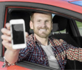 Fahrer eines Autos hält ein Smartphone hoch