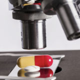 Unter einem Mikroskop liegen zwei Tabletten.