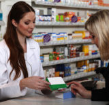 Apothekerin hält ein Medikament in der Hand und berät eine Kundin, Apotheke, Beratung