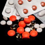 Mehrere verschiedene Tabletten in rot, weiß und transparent auf weißem Untergrund
