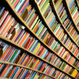 abgerundetes Bücherregal gefüllt mit vielen farbigen Büchern