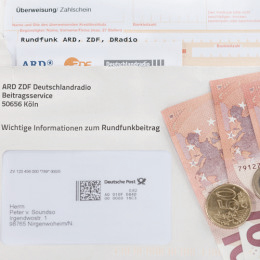 GEZ Rundfunkbeitrag, Rundfunkgebühren, Bescheid mit beiliegender Überweisung in einem Briefumschlag auf dem Geld liegt