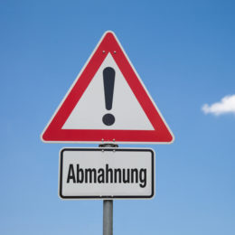 Der Schriftzug Abmahnung befindet sich unterhalb eines 'Achtung'-Schildes, das man auch im Straßenverkehr vorfindet