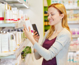 Frau scannt in der Apotheke den Code eines Kosmetikprodukts mithilfe ihres Smartphones