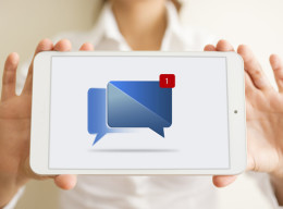 Frau hält ein Tablet, auf dem eine neue Nachricht beim Facebook Messenger angezeigt wird