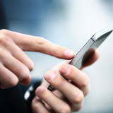 Mann hält Handy in den Händenu nd tippt mit einem Finger auf das Touchscreen-Display