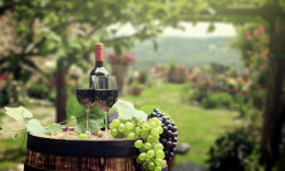 Weinfass auf dem zwei Gläser mit Rotwein und eine Flasche Rotwein steht