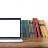 Laptop auf dem Tisch mit Büchern im Hintergrund
