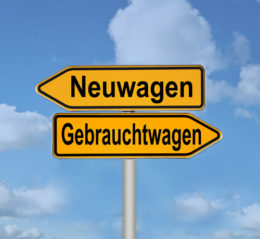 Straßenschild nach links zeigend mit Aufschrift "Neuwagen" und darunter ein Schild nach rechts zeigend mit der Aufschrift "Gebrauchtwagen".