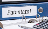 Patentamt-Ordner liegt auf einem offenen Ordner mit Taschenrechner
