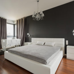 Ein weißes Doppelbett mit grauer Matraze in einem modern gestalteten Raum