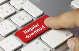 Finger drück auf eine rote Taste auf einer Tastatur mit der Aufschrift "illegaler download"
