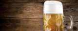 Bier in einem Maßkrug vor einem rustikalen Hintergrund.