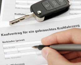Formular eines Kaufvertrags für gebrauchte Kraftfahrzeuge, Hand mit Kugelschreiber und Autoschlüssel, Gebrauchtwagen