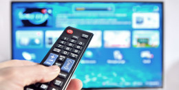 Fernbedienung vor dem verschwommenen Bild eines Fernsehers
