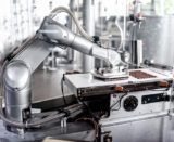 Roboterarm der in einer Fabrikhalle Schokolade produziert