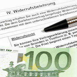 Ein 100€ Schein liegt mit einem Kulli auf einer Widerrufsbelehrung.