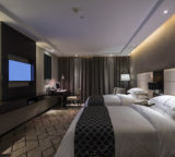 Hotelzimmer mit Bett und Fernseher an der Wand