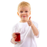 kleiner Junge hält ein Glas Fruchtsaft in der Hand und zeigt den Daumen