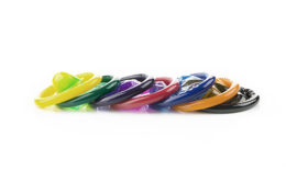 Ausgepackte Kondome in den Farben gelb, grün, lila, rot, blau, orange und schwarz auf weißem Hintergrund